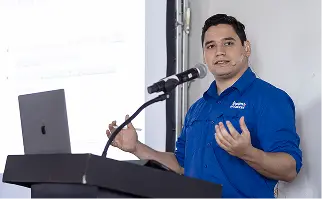 Conferencista de Panamá en Salarios con uniforme azul presentando en podio con micrófono