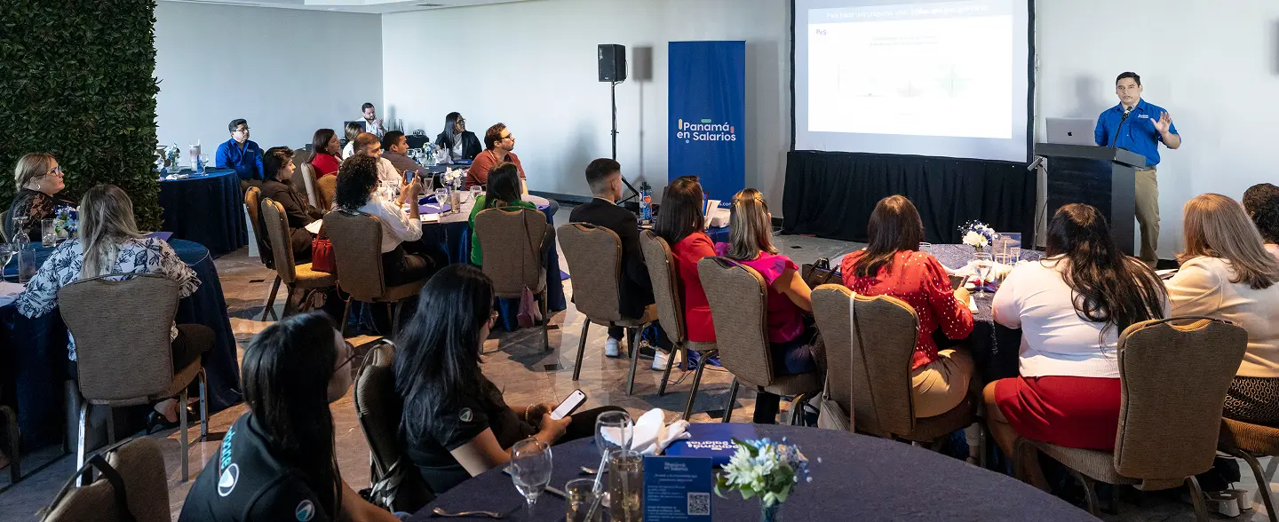 Evento de Panamá en Salarios con asistentes en mesas y conferencista presentando en pantalla